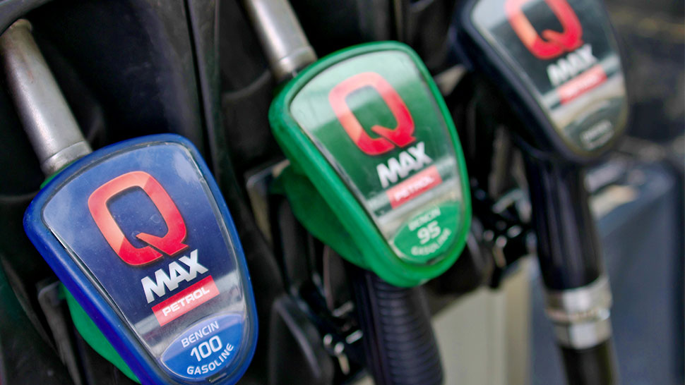 Na sliki so ročaji za točenje goriva z oznako Q Max. Vidimo tri vrste goriva: Q Max 100 (moder ročaj), Q Max 95 (zelen ročaj) in Q Max Diesel (črn ročaj).