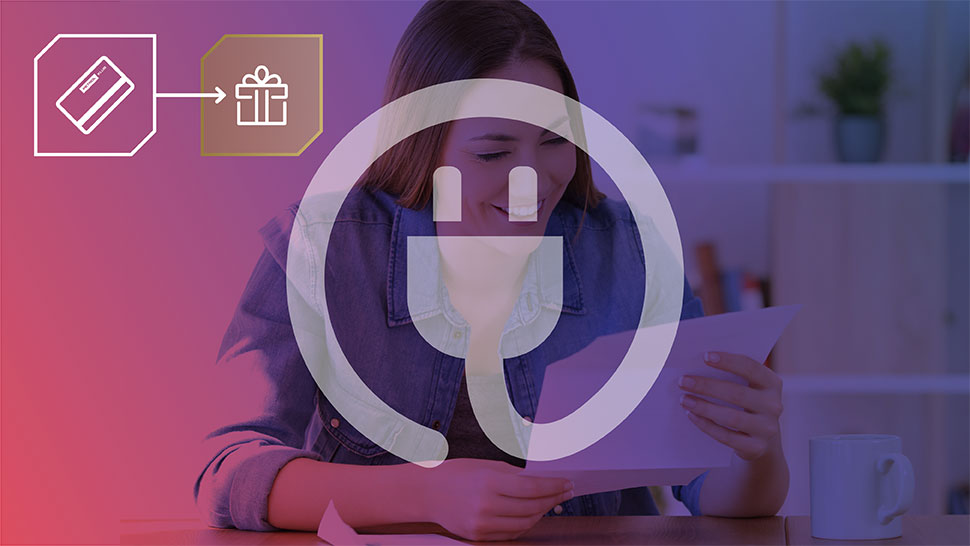 Dekle sedi za mizo in gleda v list papirja, nasmejana. Čez sliko je položen velik bel simbol električnega vtiča. V levem zgornjem kotu sta ikoni kartice in darila, povezani s puščico, ki ponazarjata nagrade ob uporabi storitev.