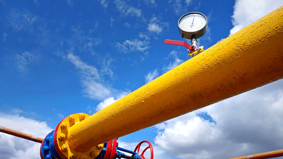 Slika prikazuje rumeno plinsko cev z merilnikom tlaka pod modrim nebom z oblaki.