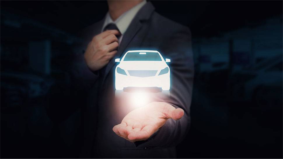 Na sliki je oseba v poslovni obleki, ki z eno roko drži svetlečo silhueto avtomobila, medtem ko si z drugo roko popravlja kravato. Ozadje je temno in zamegljeno.