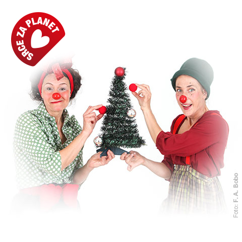 Dva klovna z rdečimi noski okrašujeta majhno božično drevesce z rdečimi noski, v levem zgornjem kotu je znak »Srce za planet«.