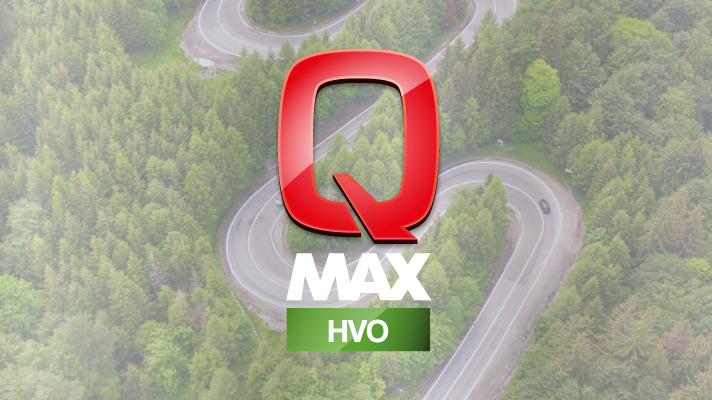 Na sliki je upodobljen logotip Q Max HVO, ki je postavljen na sredini. Ozadje prikazuje ovinkasto cesto, obdano z bujnim zelenim gozdom, kar simbolizira trajnost, naravo in okolju prijaznejše gorivo.