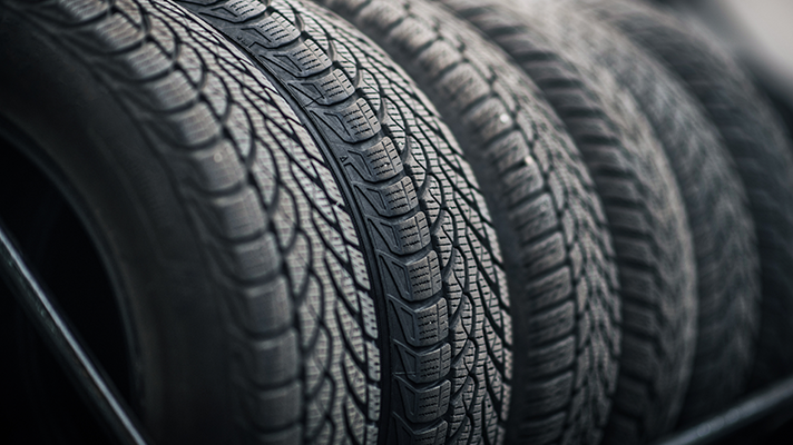 Na sliki je več avtomobilskih gum, postavljenih v vrsto na stojalu. Vidni so njihovi profili in vzorci tekalne površine.