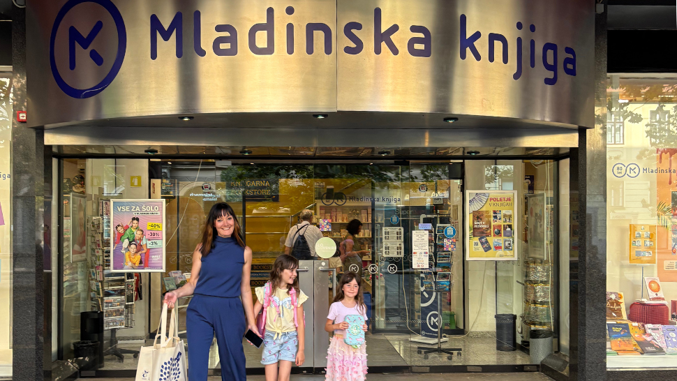 Nasmejana mama z dvema deklicama se vrača iz nakupov pred knjigarno Mladinska knjiga.