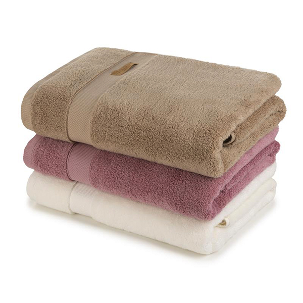 Na sliki so lepo zložene brisače v bež, rožnati in rjavi barvi. Ozadje je v nevtralni beli barvi.