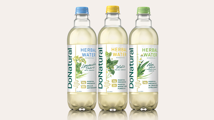 Na svetlem, nevtralnem ozadju so v vrsti postavljene tri prozorne plastenke pijače Donat Natural. V vsaki je rahlo motna, svetla pijača z vidnimi mehurčki. Plastenke imajo različne barve pokrovčkov – leva modrega, srednja zelenega in desna rumenega. Na etiketah je napis »Donat Natural« ter »Herbal Water«, pod katerim so prikazane stilizirane ilustracije zelišč. Vsaka plastenka predstavlja drug okus, kar nakazujejo barve pokrovčkov in grafični poudarki na etiketi.