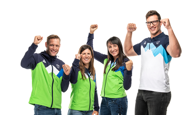 Štirje slovenski olimpijci v športnih oblačilih se smejijo in z dvignjenimi pestmi navijajo.