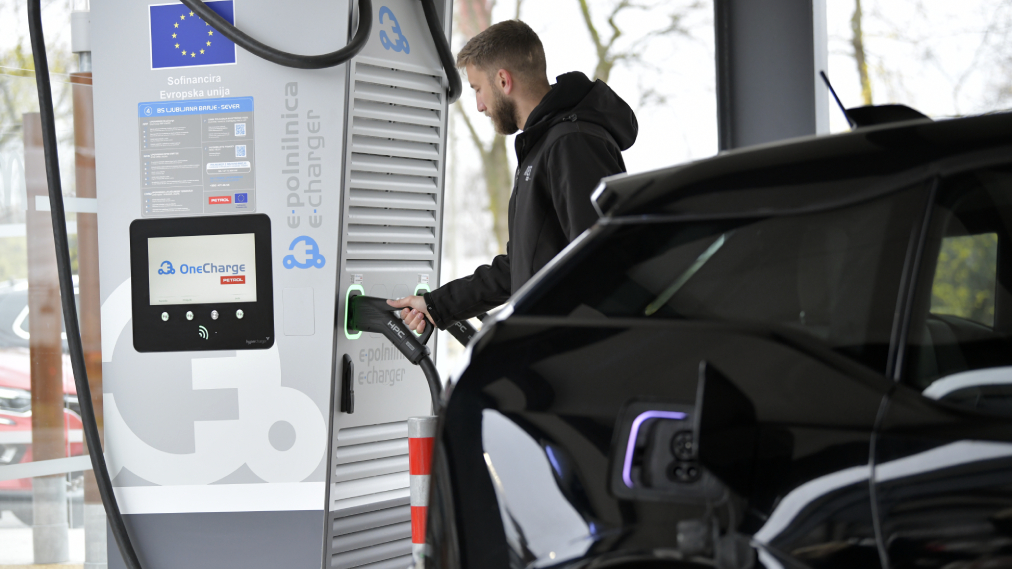 Na sliki je električno vozilo med polnjenjem na javni polnilni postaji za električna vozila.